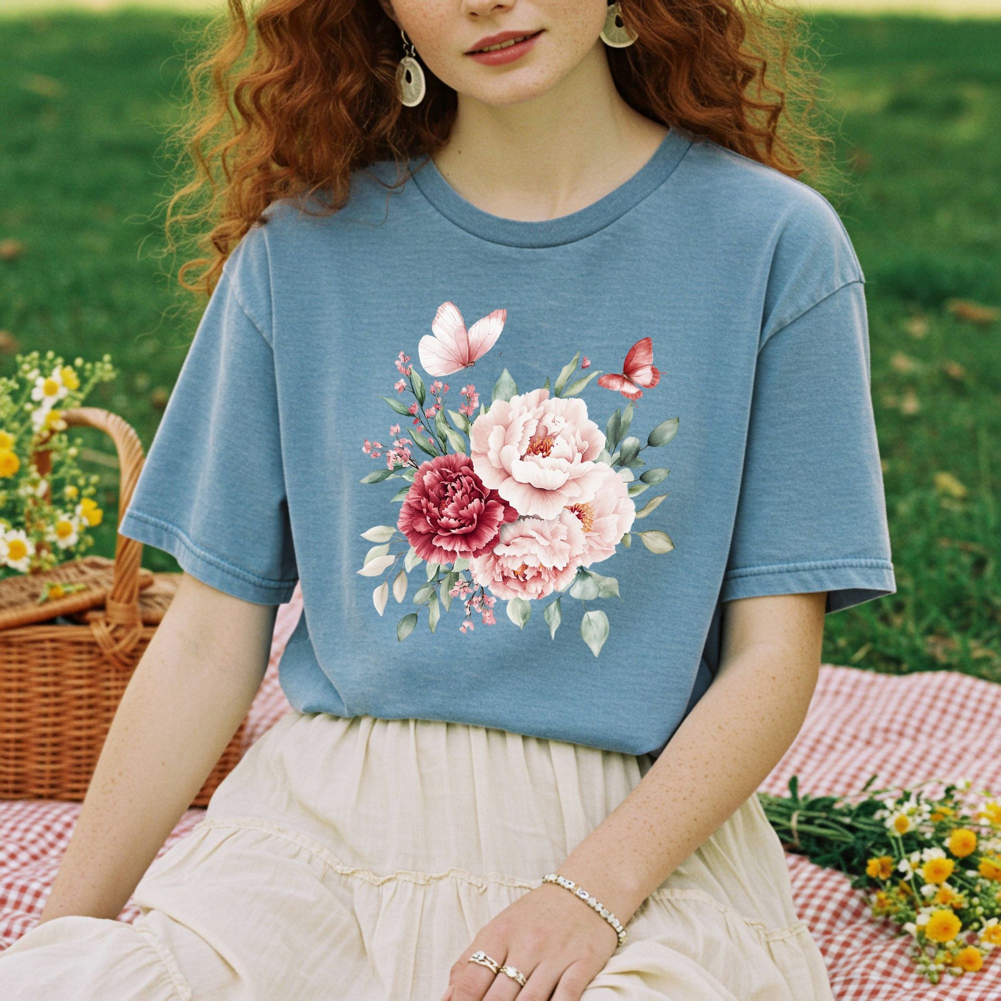 Woman in a relaxed-fit, garment-dyed blue t-shirt with a watercolor peony and butterfly bouquet design.