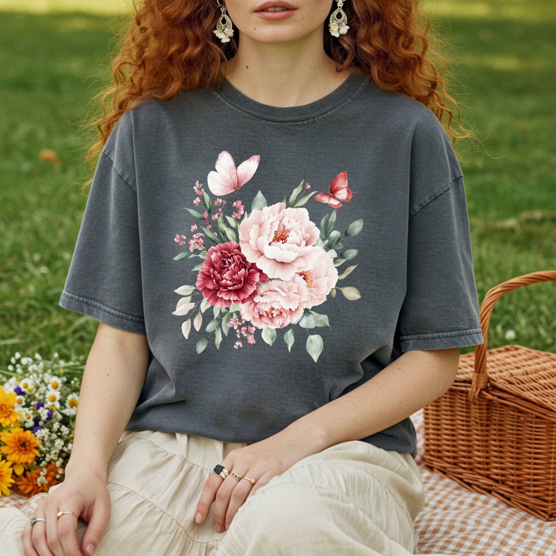 Woman in a charcoal garment-dyed cotton t-shirt with a watercolor peony and butterfly bouquet design.