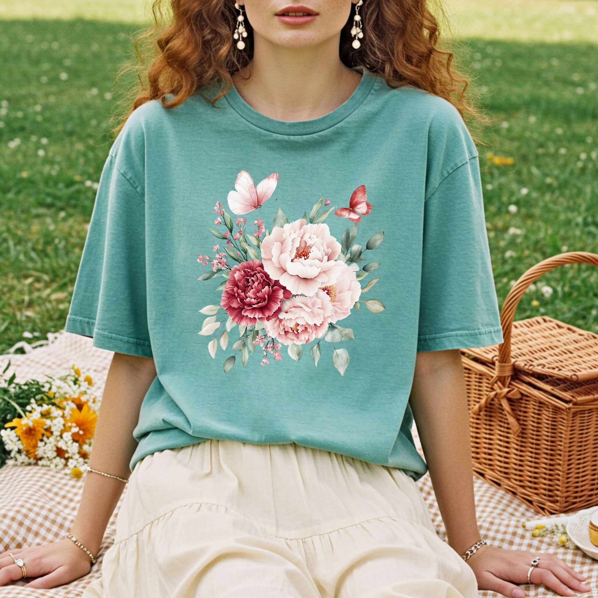 Woman in a relaxed-fit, garment-dyed teal t-shirt with a vintage peony and butterfly bouquet design.