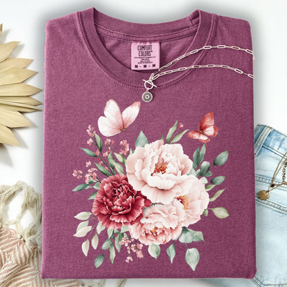 Berry garment-dyed cotton t-shirt with a vintage peony and butterfly watercolor design, folded with a silver necklace.
