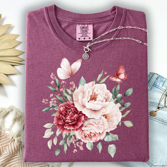 Berry garment-dyed cotton t-shirt with a vintage peony and butterfly watercolor design, folded with a silver necklace.