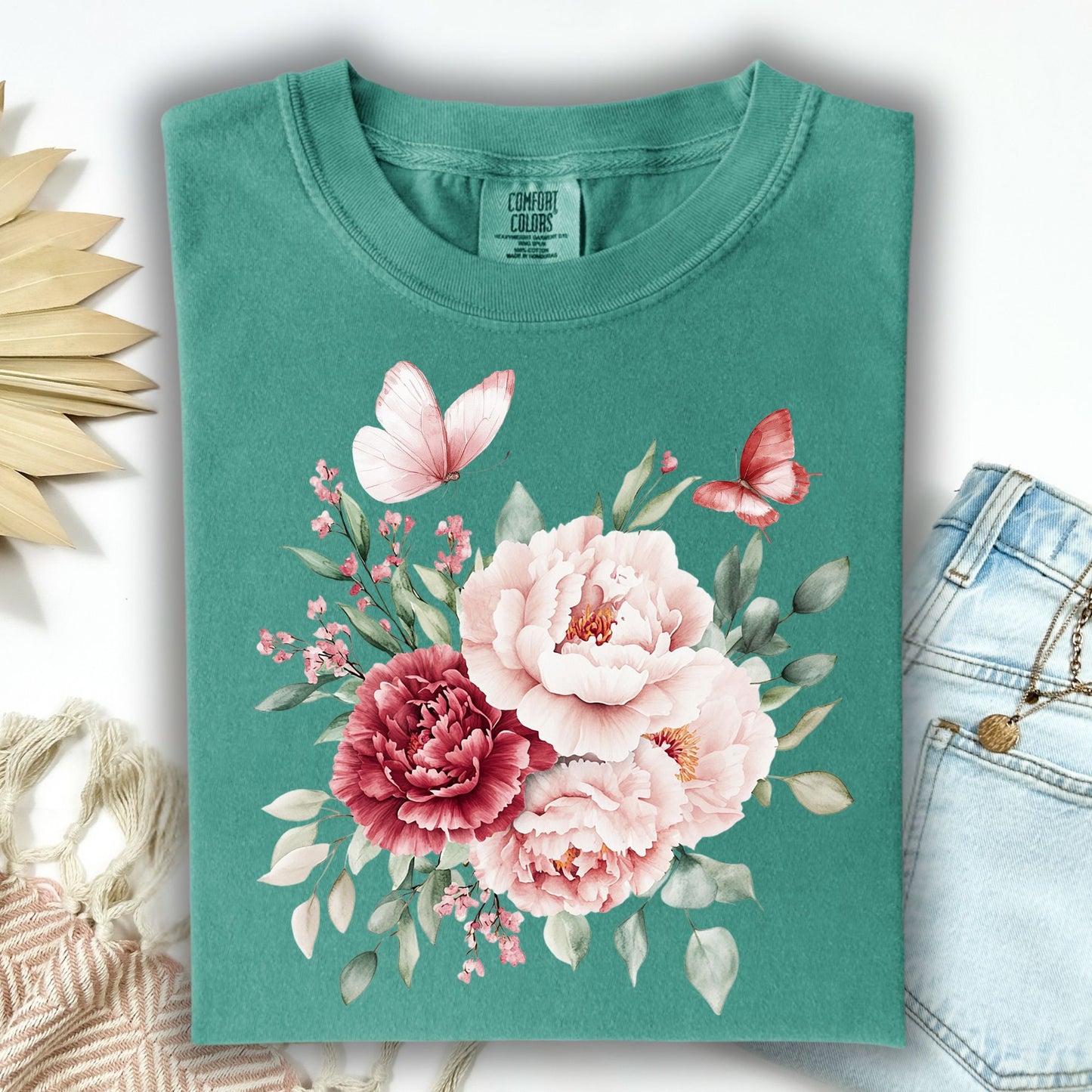 Seafoam green garment-dyed cotton t-shirt with a watercolor peony and butterfly bouquet design.
