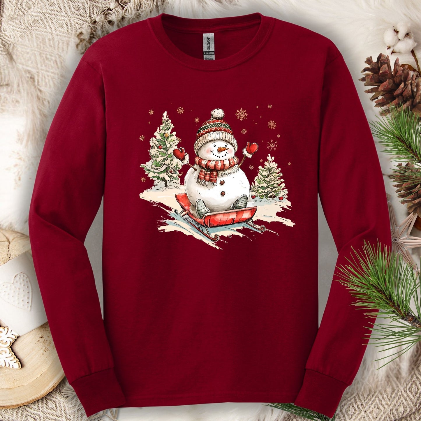 Cardinal Red Gildan long sleeve tee with a vintage snowman sledding design.