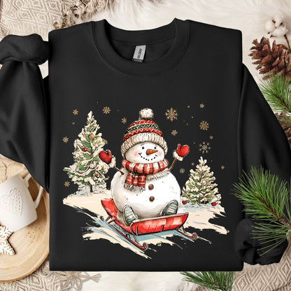 Black Gildan sweatshirt with a vintage snowman sledding design, festive trees, and snowflakes.