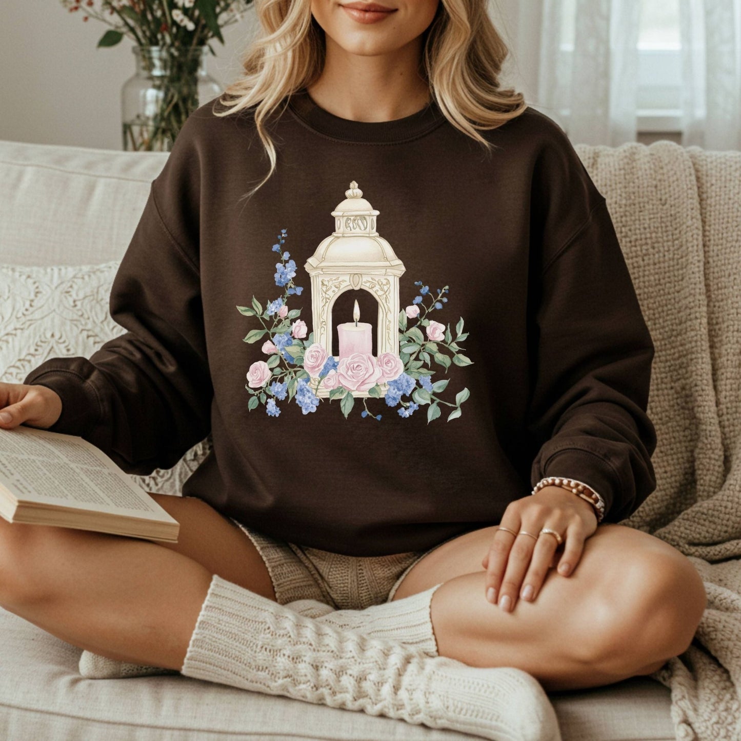 Woman in a dark brown crewneck sweatshirt with a delicate embroidered lantern and watercolor-style roses.