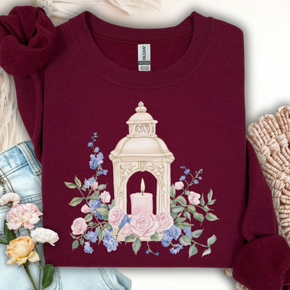 Maroon crewneck sweatshirt with embroidered lantern, pink candle, and watercolor-style roses and sprigs.