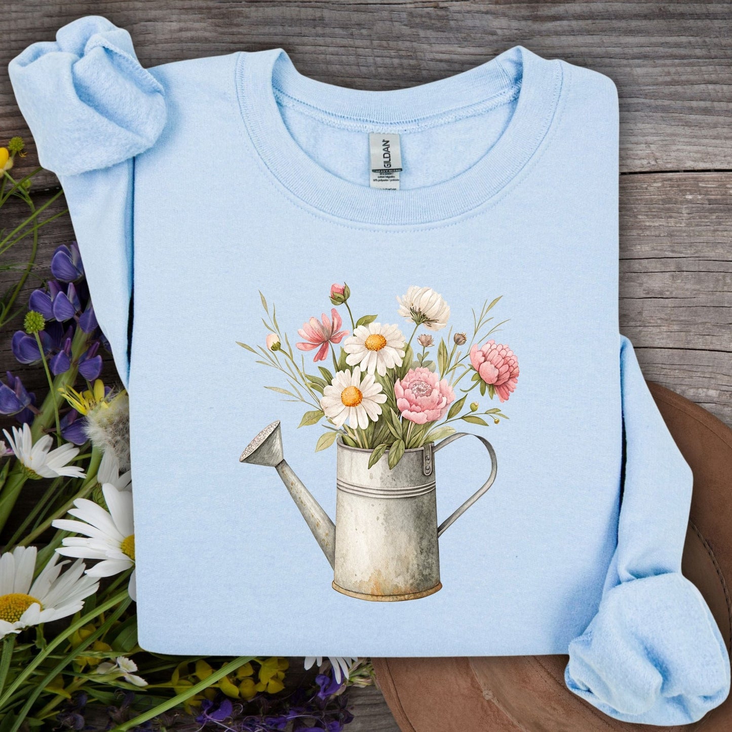 Light blue S-sized sweatshirt with a vintage watering can and mixed floral illustration.