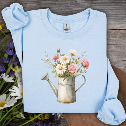 Light blue S-sized sweatshirt with a vintage watering can and mixed floral illustration.