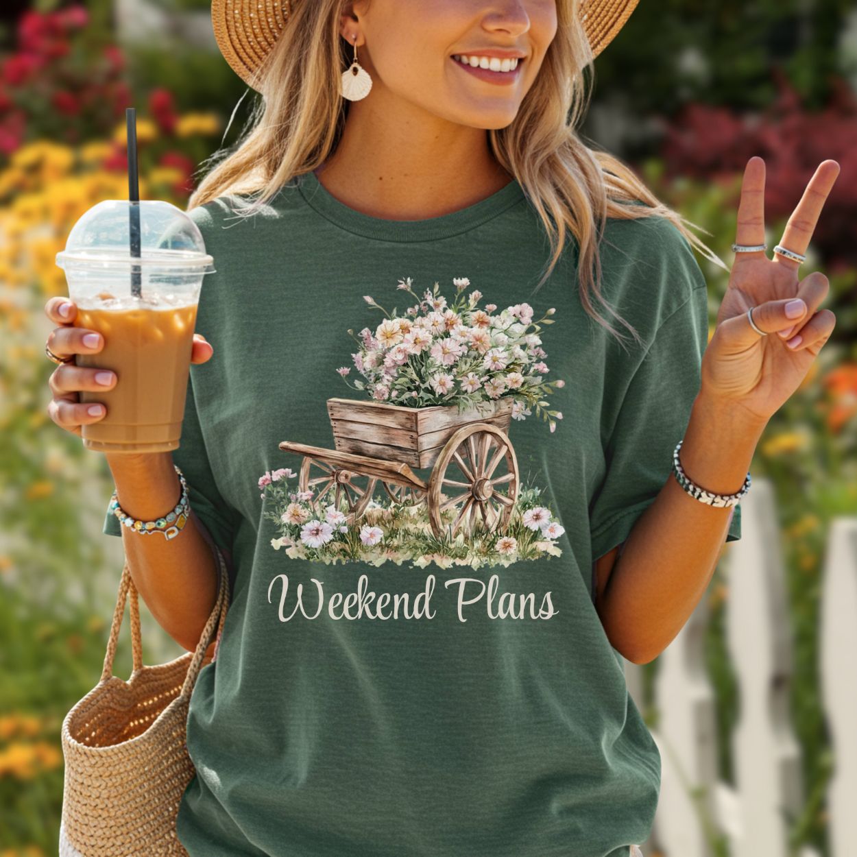 Woman in a relaxed-fit, garment-dyed forest green t-shirt with a rustic gardening wagon and carnations design.
