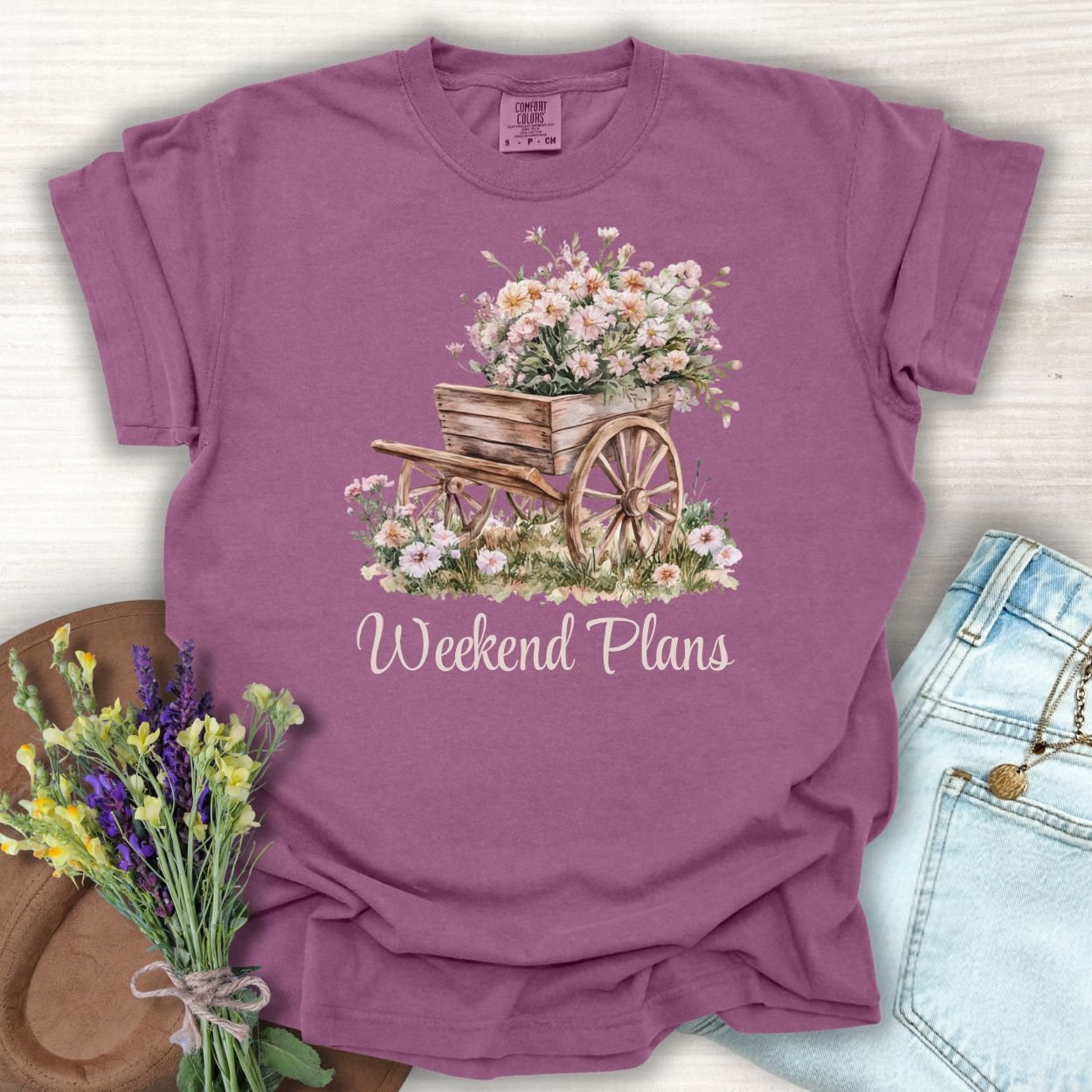 Berry S-sized cotton t-shirt with a watercolor gardening wagon overflowing with carnations and "Weekend Plans" text.