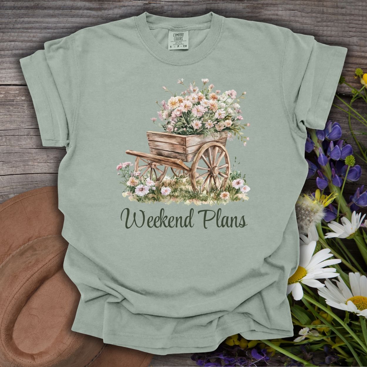 Bay green garment-dyed cotton t-shirt with a watercolor rustic gardening wagon overflowing with pink carnations and "Weekend Plans" text.