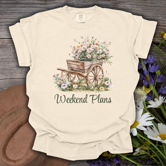Ivory relaxed-fit cotton t-shirt with a watercolor gardening wagon overflowing with carnations and "Weekend Plans" text.