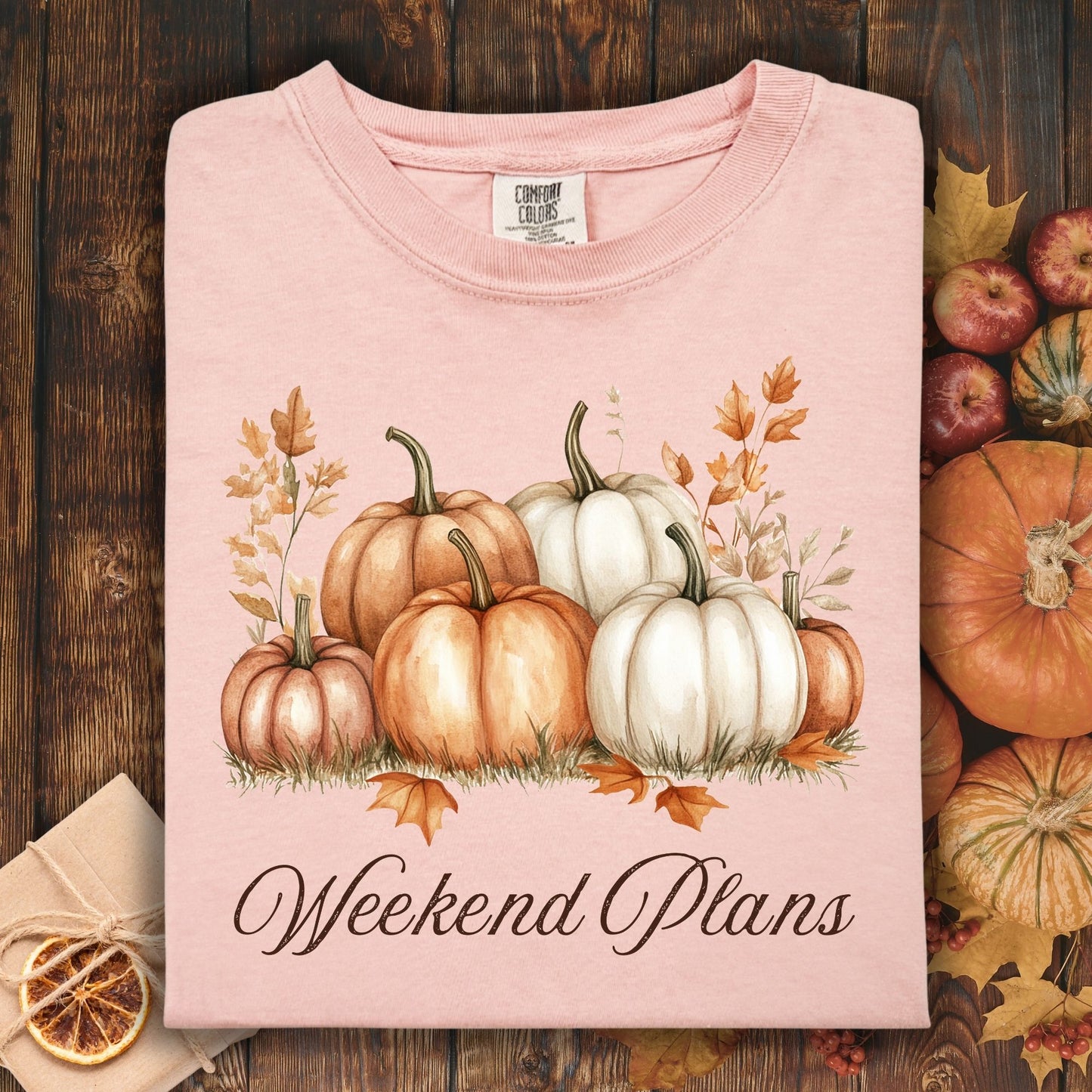 Peachy Comfort Colors t-shirt with watercolor pumpkins and "Weekend Plans" text, surrounded by fall decor.