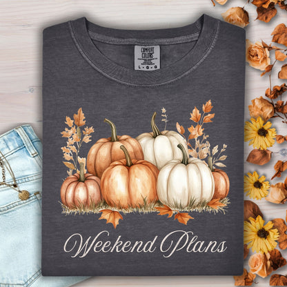 Pepper-colored heavyweight cotton t-shirt with watercolor pumpkins, fall leaves, and "Weekend Plans" text.