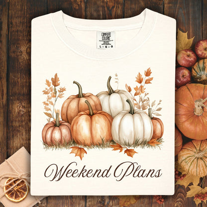 Ivory heavyweight cotton t-shirt with watercolor pumpkins and "Weekend Plans" text, surrounded by fall decor.