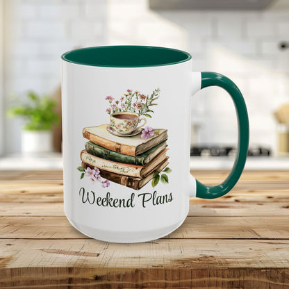 White 15oz ceramic mug with green handle and interior, featuring a watercolor stack of books, floral teacup, and "Weekend Plans" text.