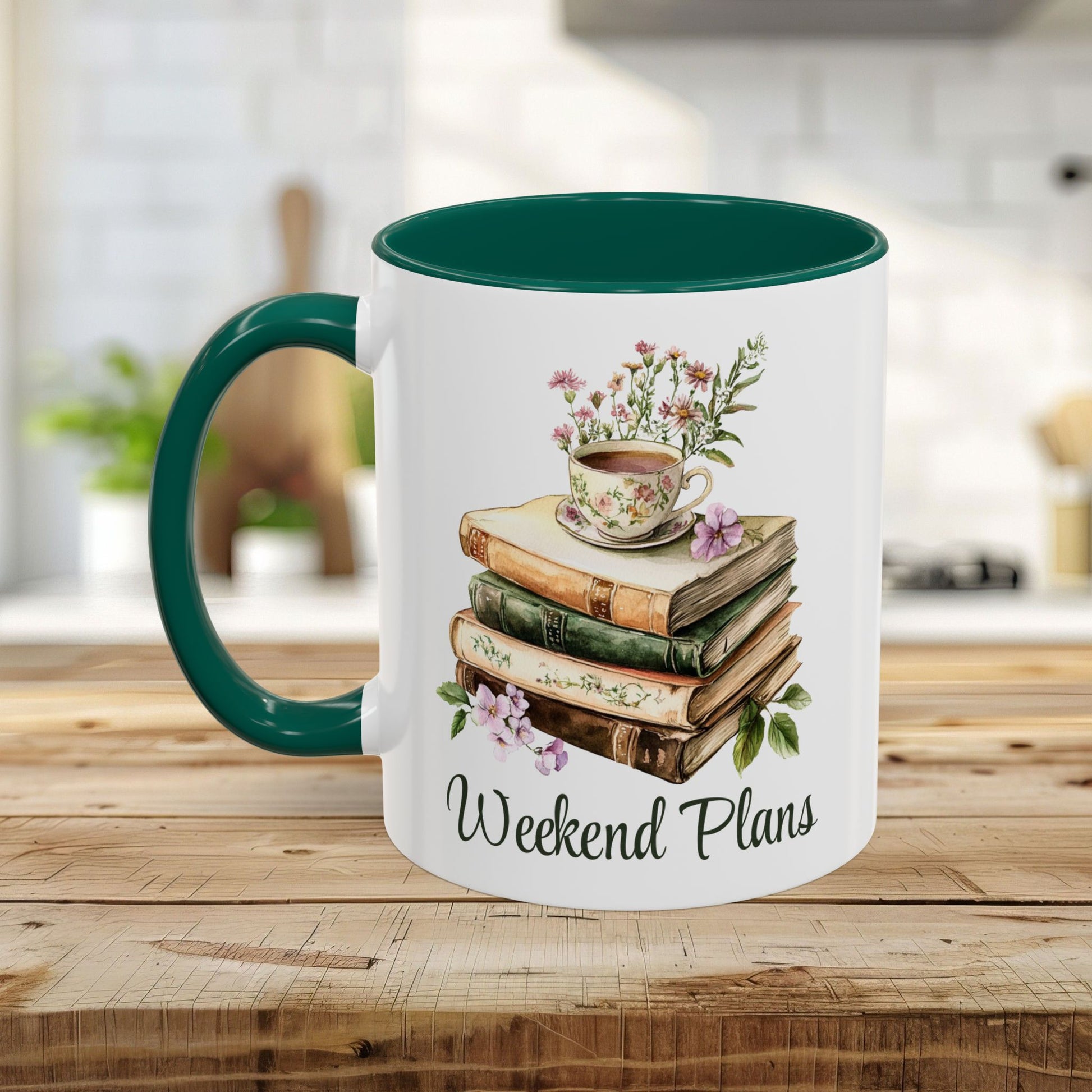 White ceramic mug with a dark green handle and interior, featuring a watercolor stack of books, a floral teacup, and "Weekend Plans" text.