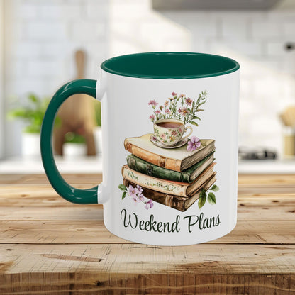 White ceramic mug with a dark green handle and interior, featuring a watercolor stack of books, a floral teacup, and "Weekend Plans" text.