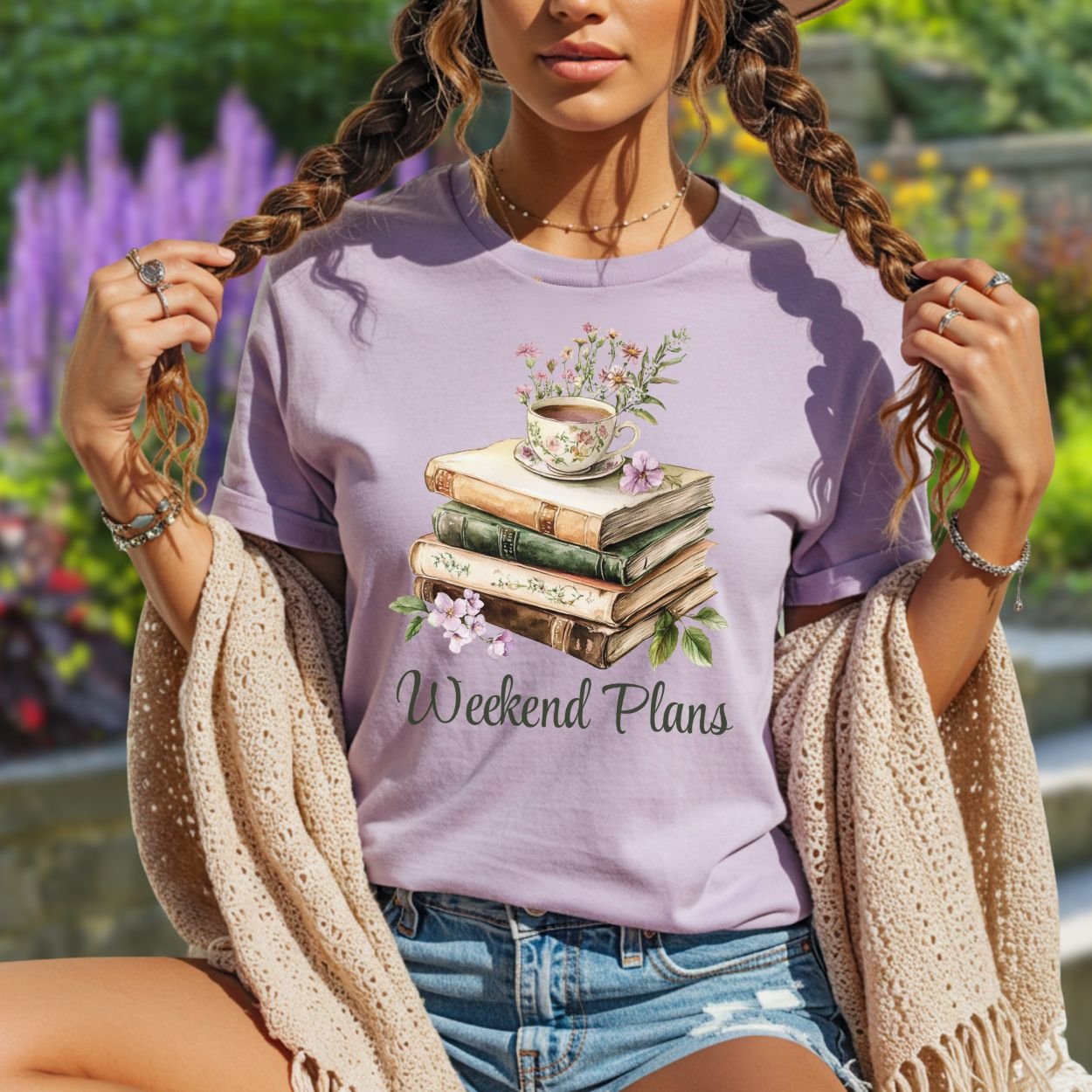 Lavender t-shirt with a watercolor stack of vintage books, floral teacup, and "Weekend Plans" text.
