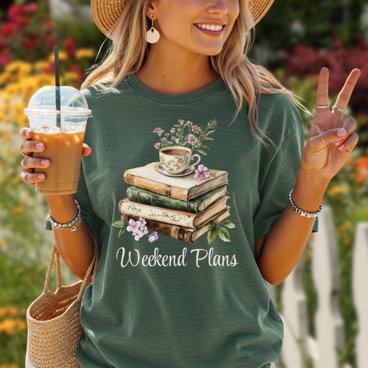 Woman in a relaxed-fit, garment-dyed forest green t-shirt with a "Weekend Plans" book stack and teacup graphic.