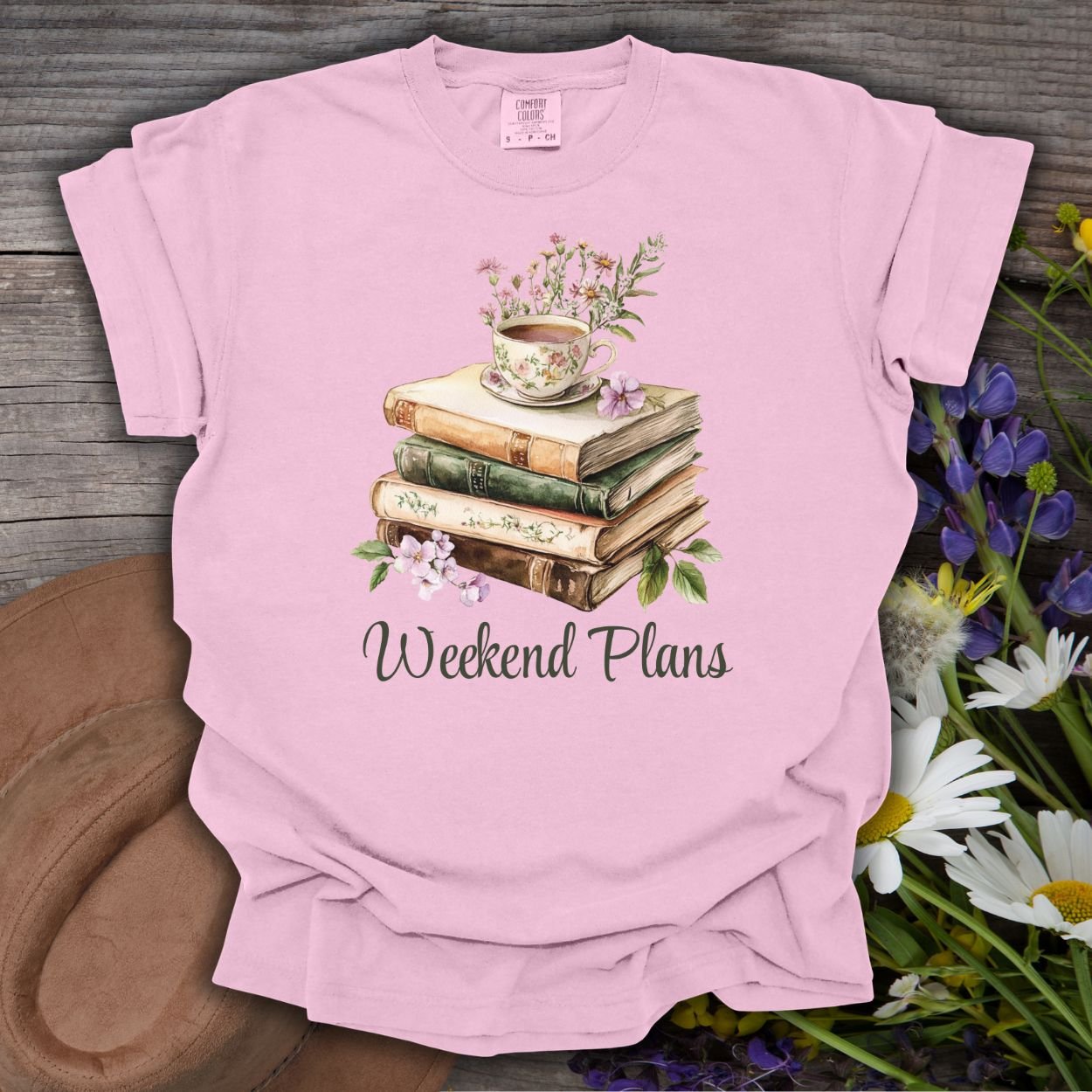 Blossom pink garment-dyed t-shirt with a watercolor stack of vintage books, floral teacup, and "Weekend Plans" text.