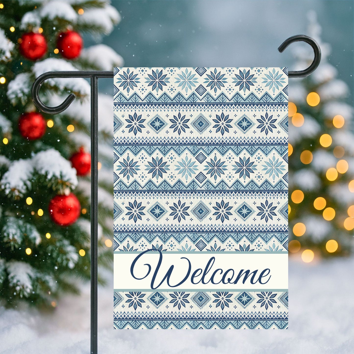 Blue Fair Isle pattern garden flag with "Welcome" script, 12'' × 18'' poly poplin canvas, on a snowy background.