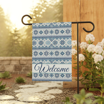 Blue Fair Isle pattern garden flag with "Welcome" in script, made of poly poplin canvas, hanging on a black stand.