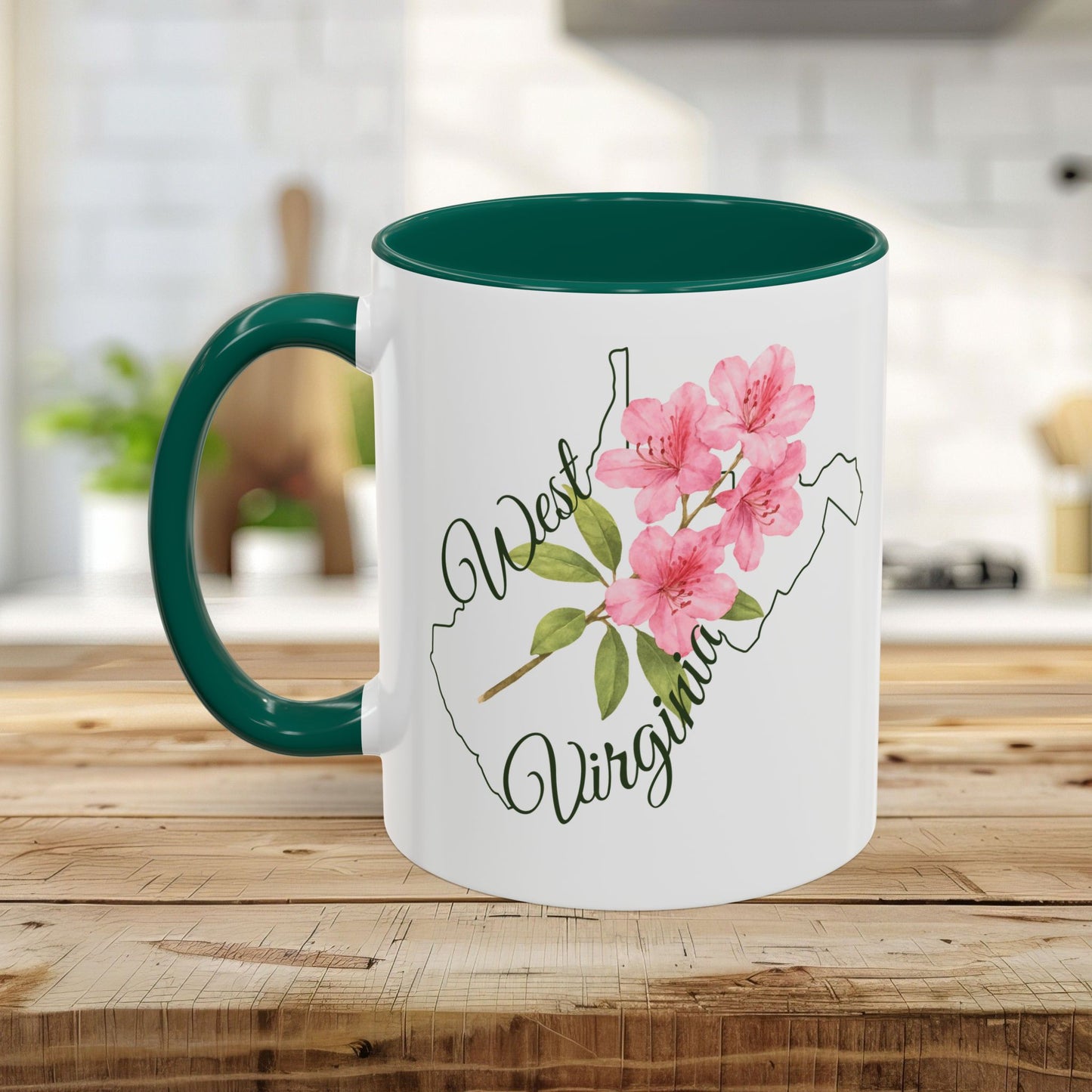 White ceramic mug with green handle and interior, featuring a pink rhododendron and "West Virginia" text over a state silhouette.