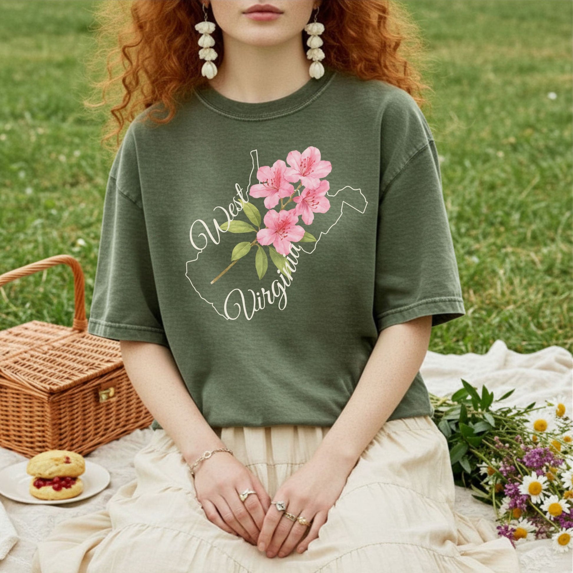 Garment-dyed olive green t-shirt with a white West Virginia outline and pink rhododendron graphic.