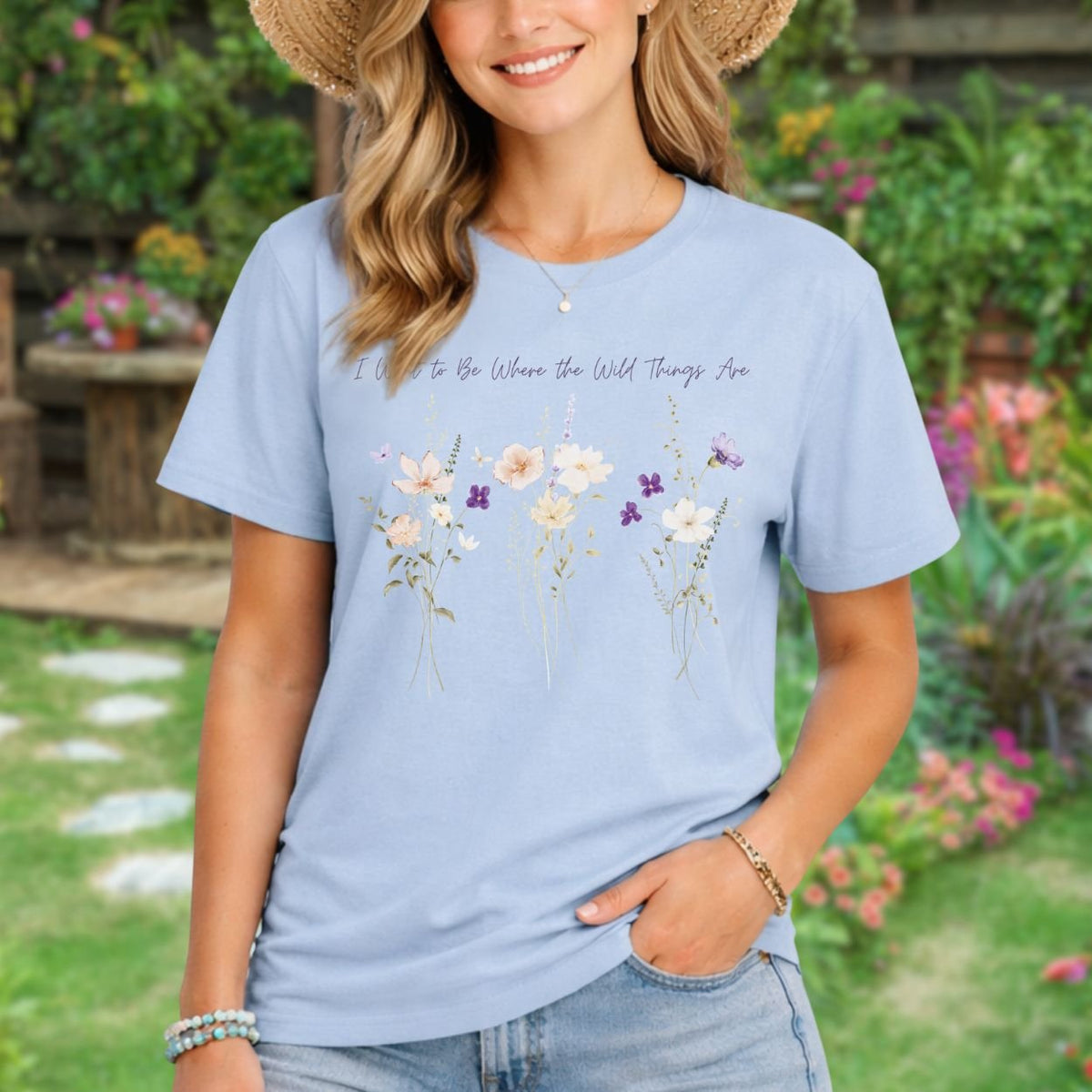 Relaxed-fit light purple cotton t-shirt featuring watercolor wildflowers and hand-lettered text in a garden setting.
