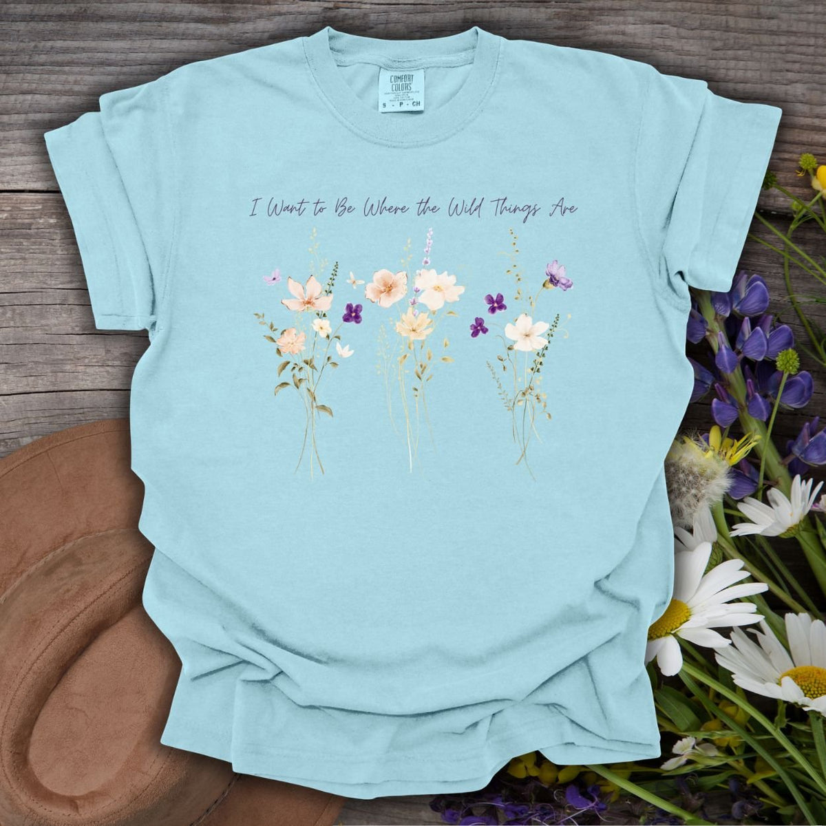Chambray blue garment-dyed cotton t-shirt featuring watercolor wildflowers and the text I Want to Be Where the Wild Things Are.