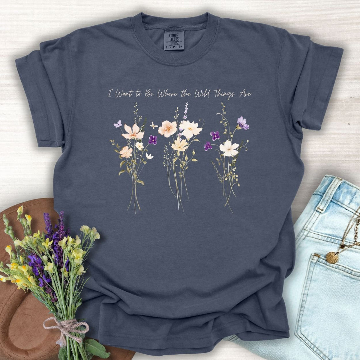 Denim blue garment-dyed cotton t-shirt featuring watercolor wildflowers and the text I Want to Be Where the Wild Things Are.