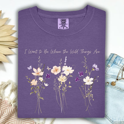 Grape Comfort Colors t-shirt with "I Want to Be Where the Wild Things Are" text and cream/purple wildflowers.