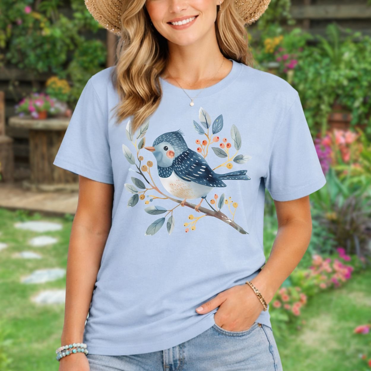 Woman in a relaxed-fit, light blue t-shirt with a whimsical watercolor bluebird on a leafy branch design.