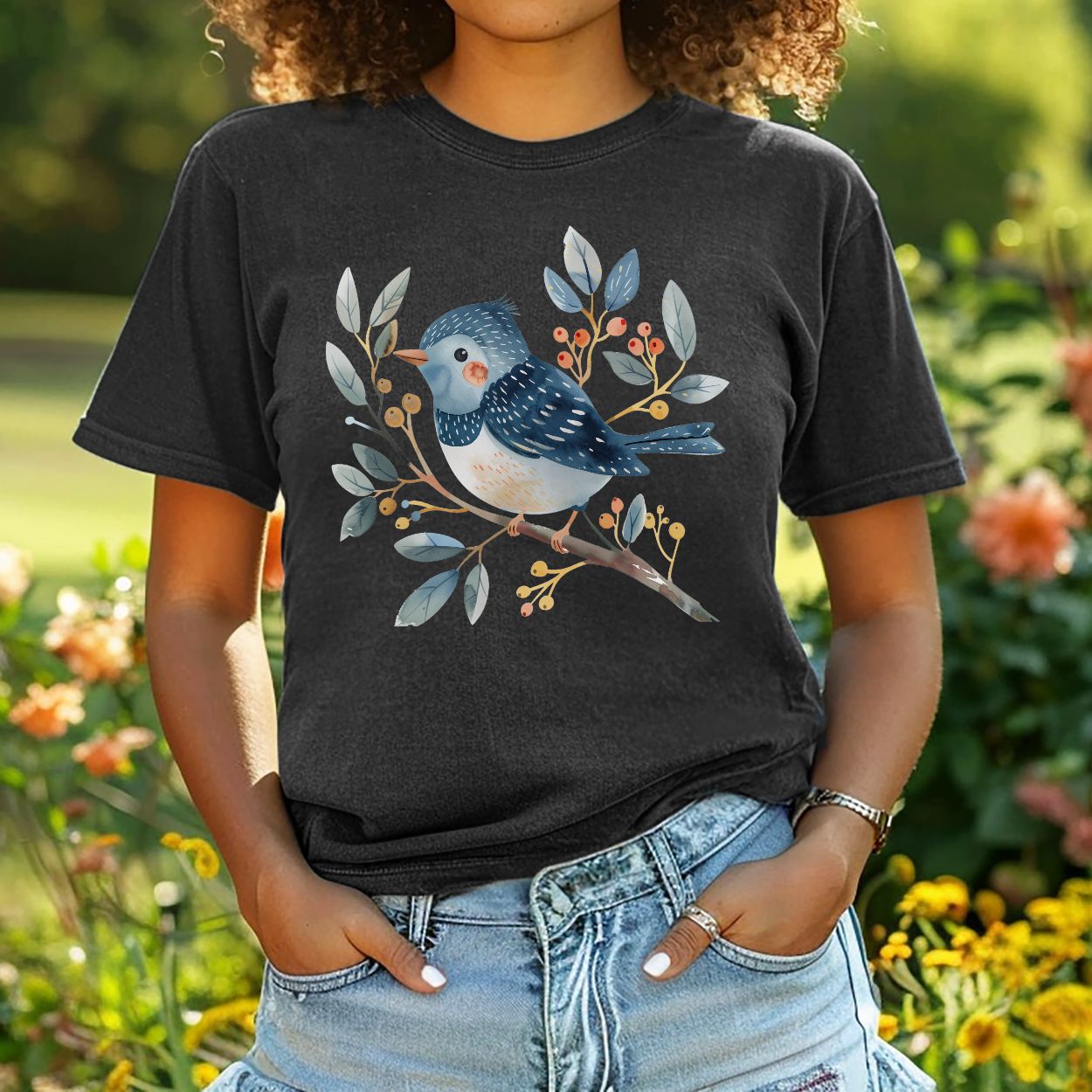 Garment-dyed black t-shirt with a whimsical bluebird on a leafy branch, accented with red and orange berries.