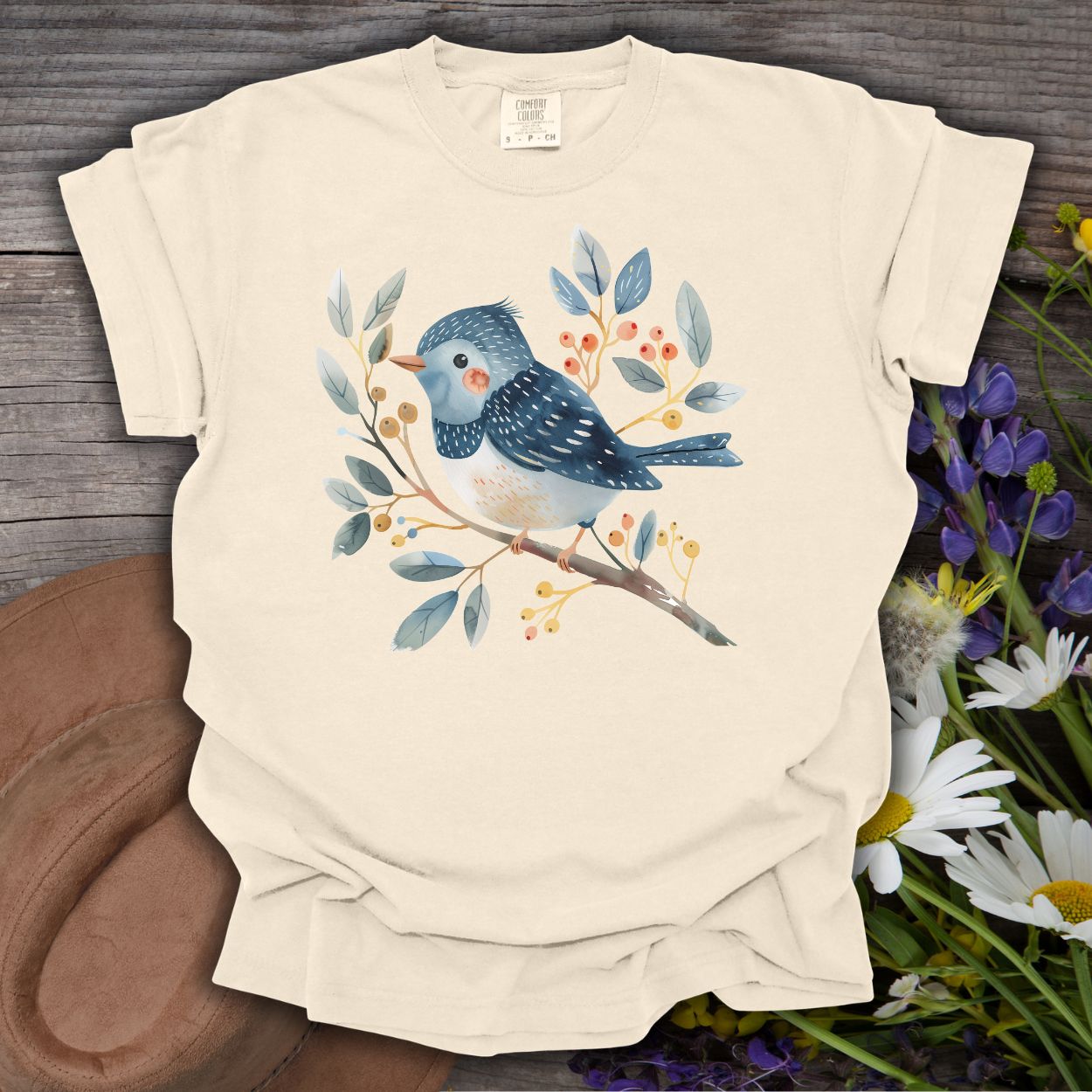 Ivory S t-shirt with a whimsical bluebird on a branch, painted in watercolor blues, reds, and oranges.
