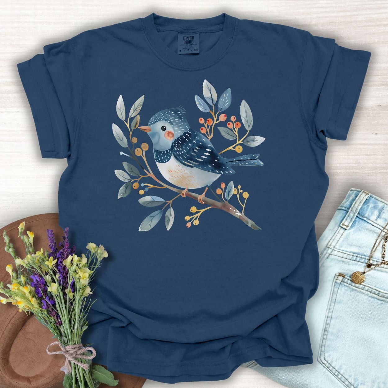 True Navy S t-shirt with a whimsical bluebird on a branch, painted in watercolor blues, reds, and oranges.
