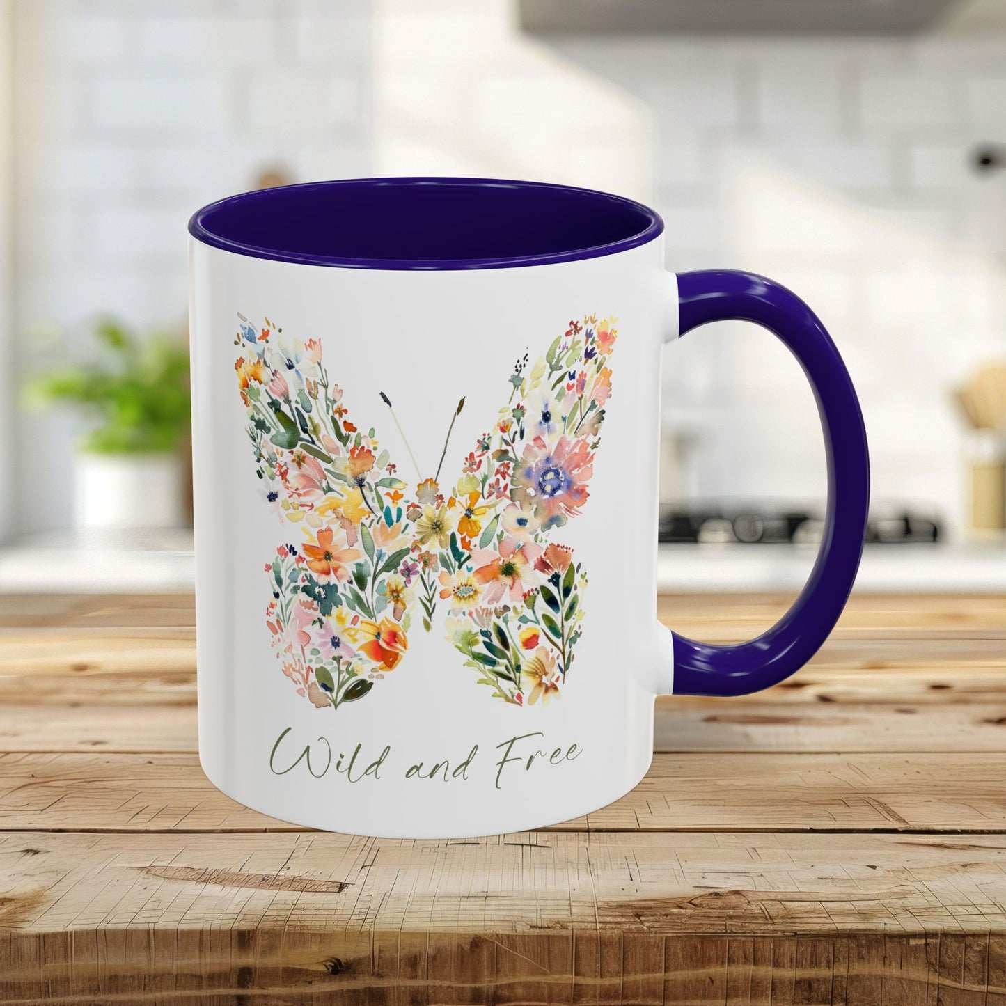 White ceramic 11oz mug with a blue interior and handle, featuring a watercolor floral butterfly and "Wild and Free" text.