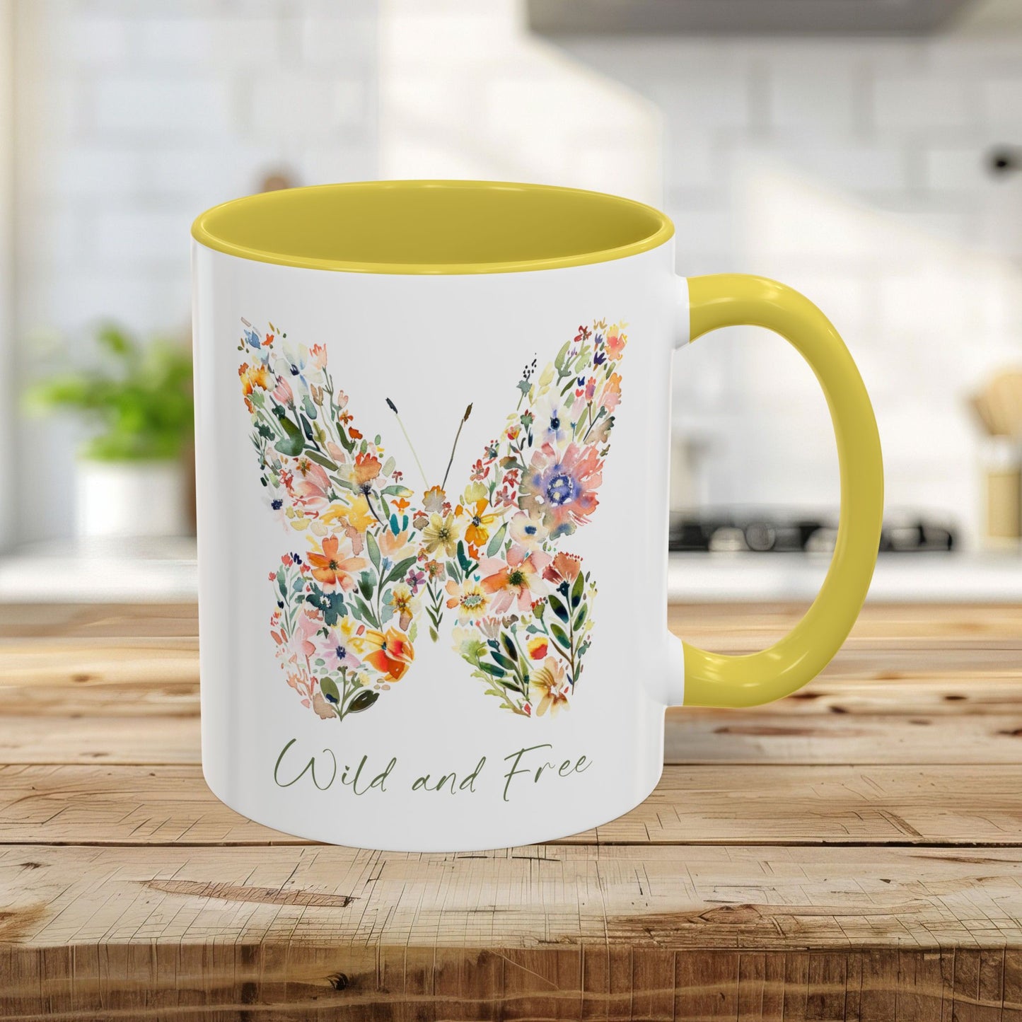 White ceramic 11oz mug with a yellow interior and handle, featuring a watercolor floral butterfly and "Wild and Free" text.