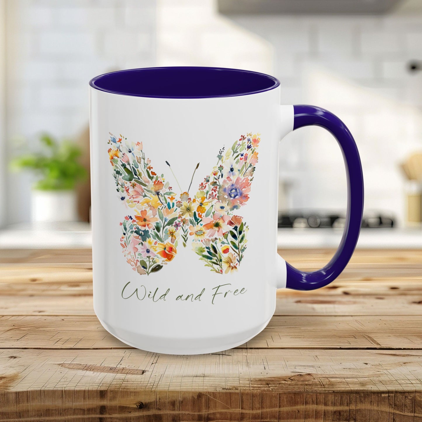 White 15oz ceramic mug with a watercolor floral butterfly and "Wild and Free" text, featuring a blue interior and handle.