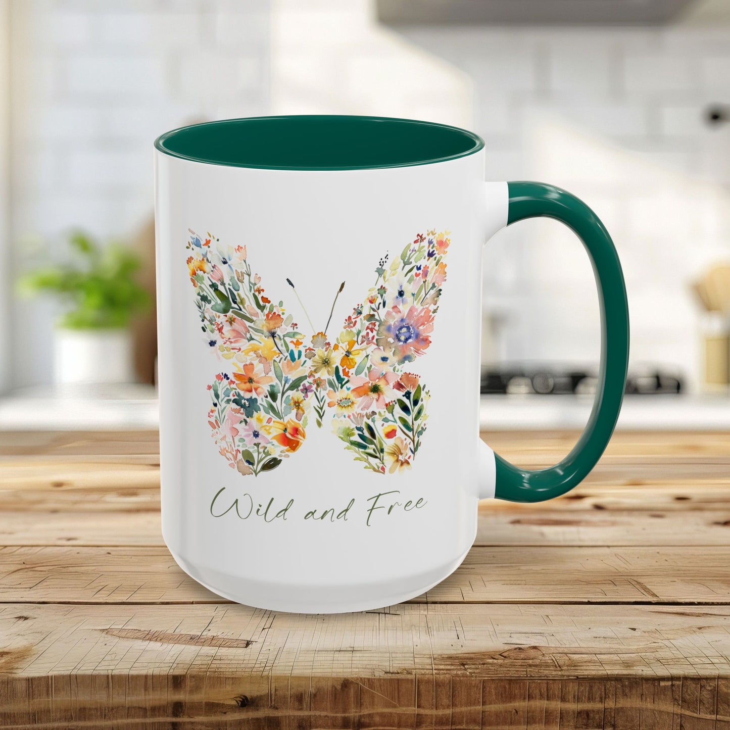 White 15oz ceramic mug with a green handle and interior, featuring a watercolor floral butterfly and "Wild and Free" text.
