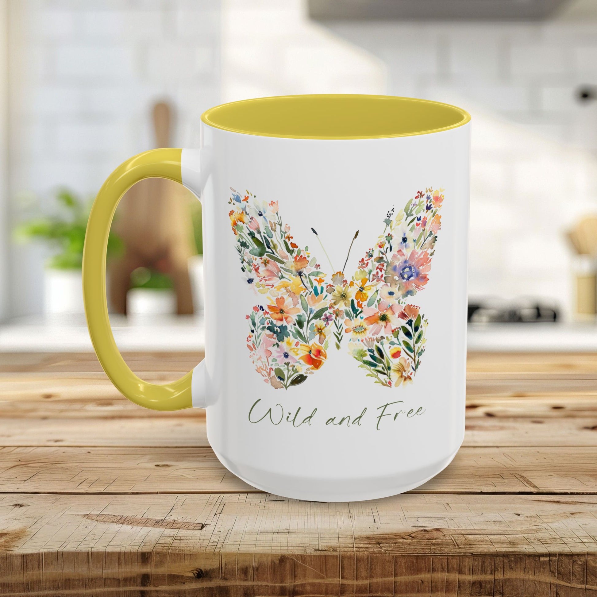 White ceramic mug with yellow handle and interior, featuring a watercolor floral butterfly and "Wild and Free" text.