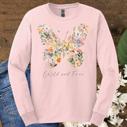 Pink long-sleeve tee with a watercolor wildflower butterfly and "Wild and Free" text, on a wooden background with jeans.
