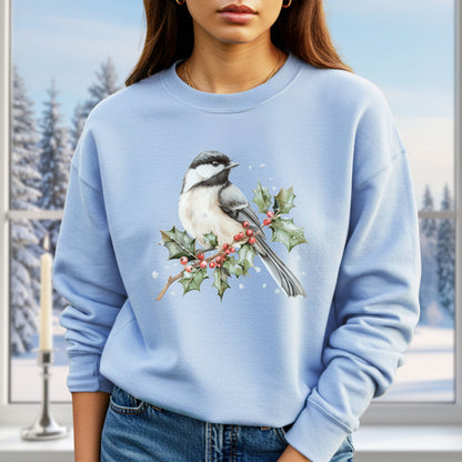 Light blue sweatshirt with a watercolor chickadee on a frosted holly branch, worn by a woman.
