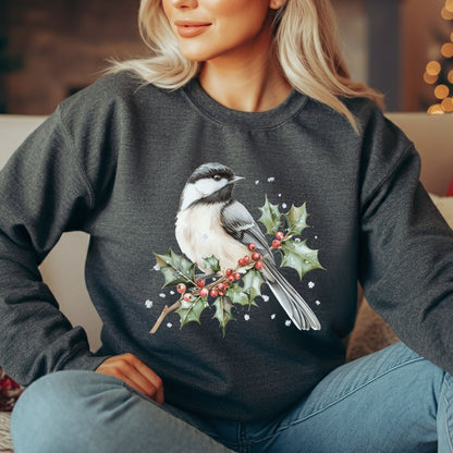 Woman wearing a dark gray crewneck sweatshirt with a watercolor chickadee on a frosted holly branch design.