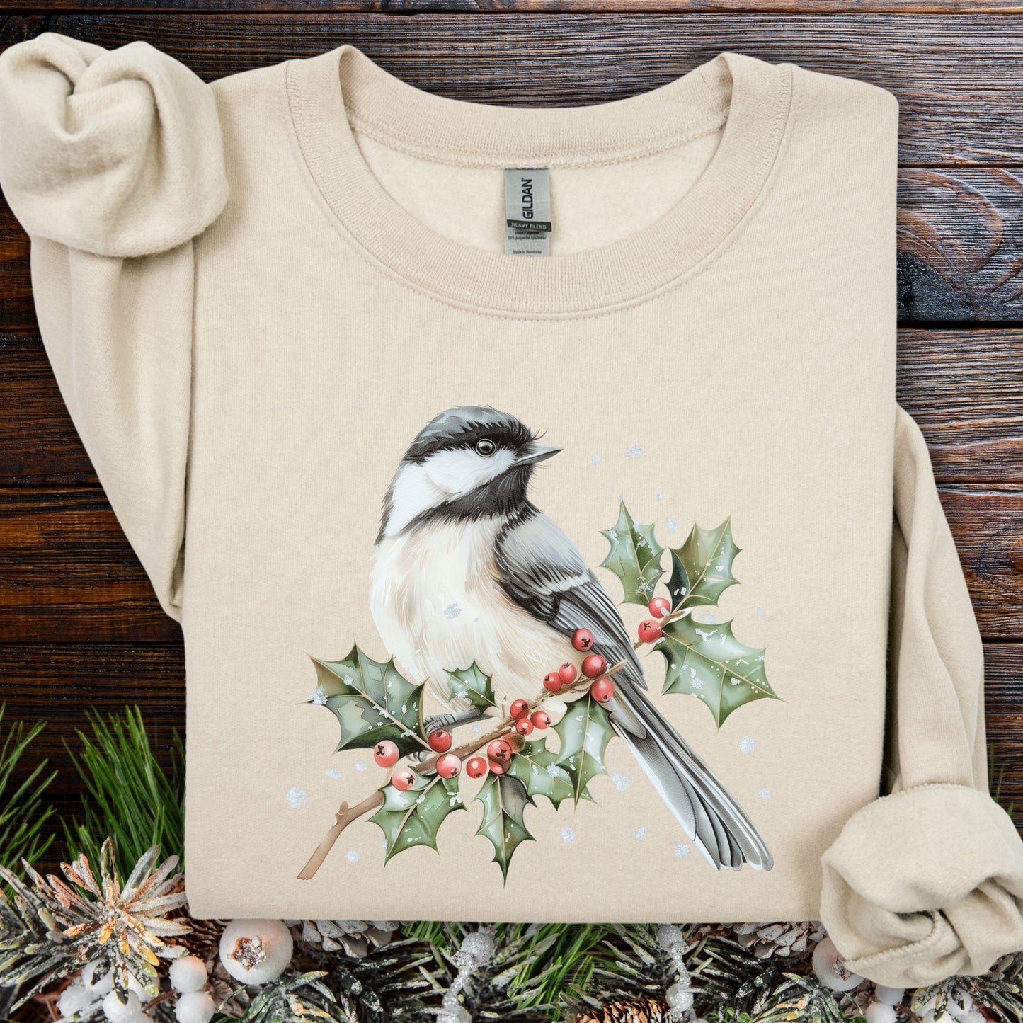 Sand crewneck sweatshirt with a watercolor chickadee on a frosted holly branch design.