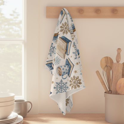 Winter Cup of Cocoa & Books microfiber kitchen towel with blue and neutral illustrations, hanging on a wooden hook.
