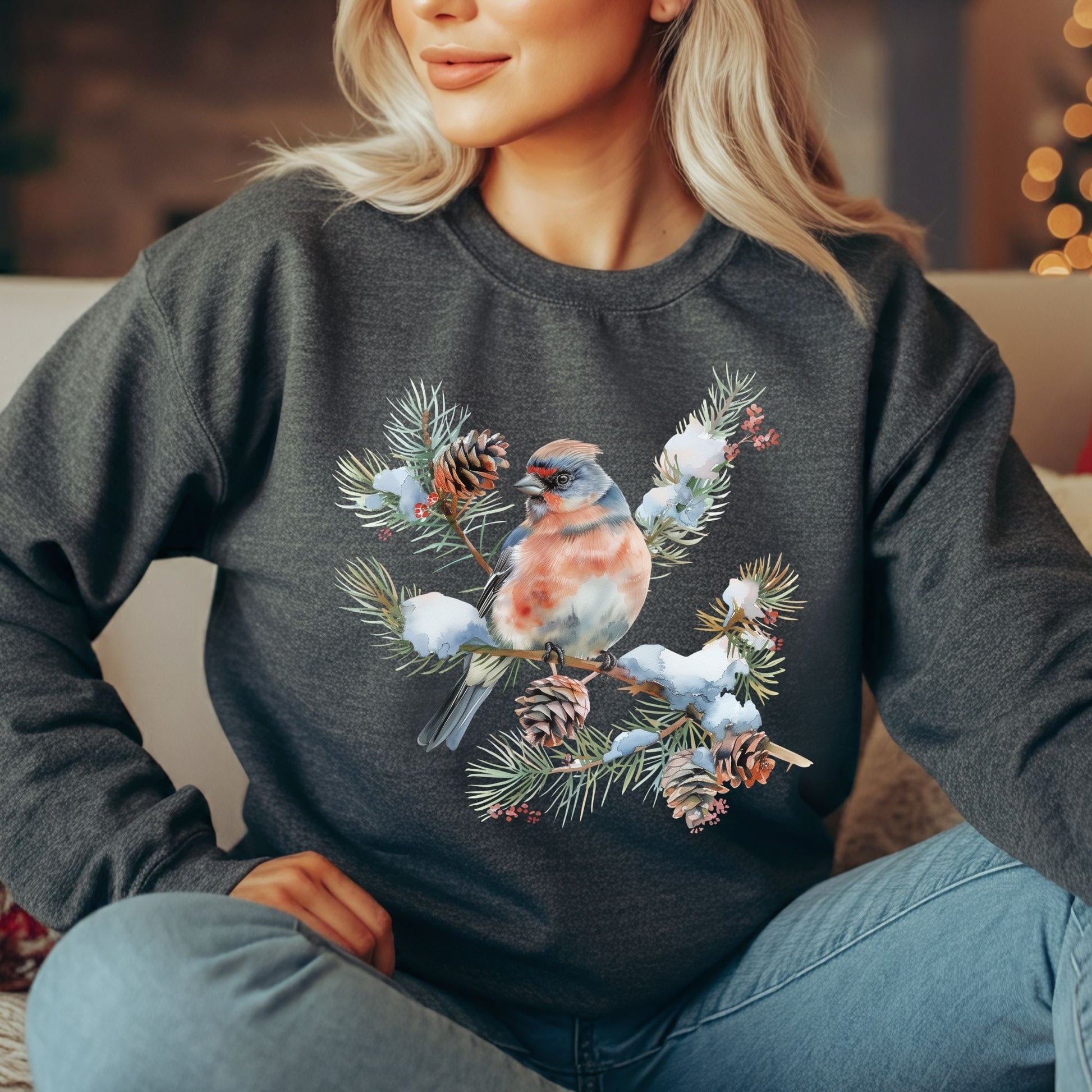 Woman wearing a charcoal gray sweatshirt with a winter bird on snowy evergreen branch design.