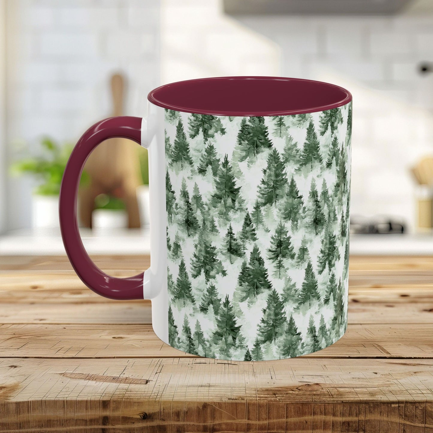 White ceramic mug with a watercolor evergreen forest pattern and a maroon handle and interior.