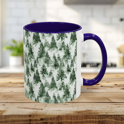 White ceramic mug with watercolor evergreen forest pattern, purple handle and interior, on a wooden surface.